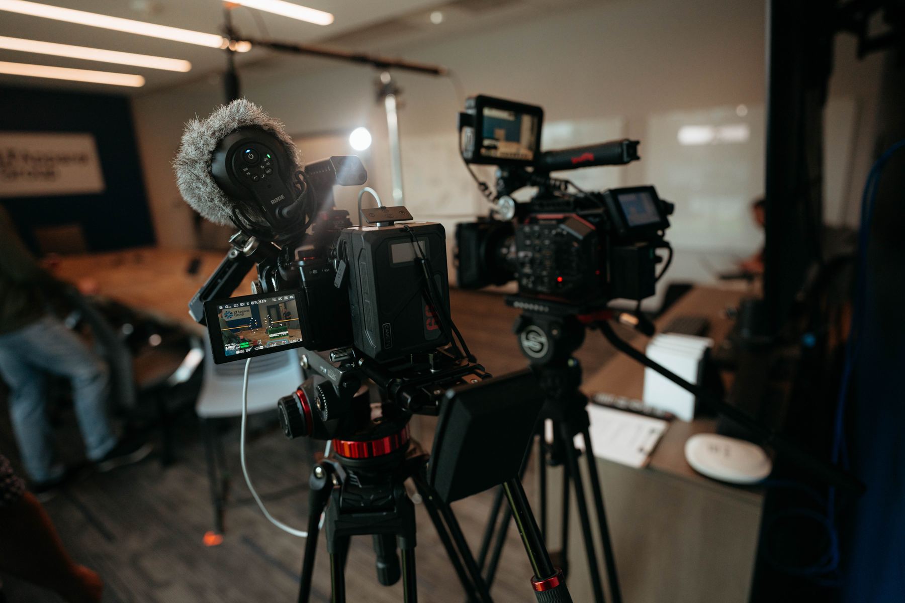 Two cameras set up and aimed at the interview chair in a conference room