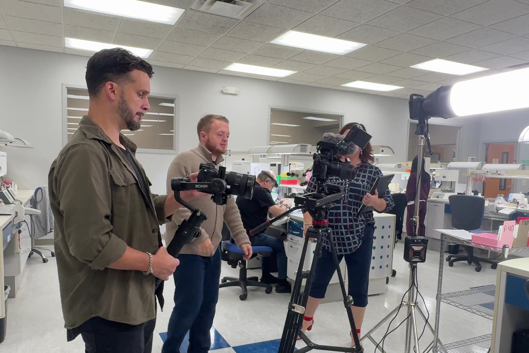 Crew filming in a dental lab with a gimbal and a tripod camera while the client watches