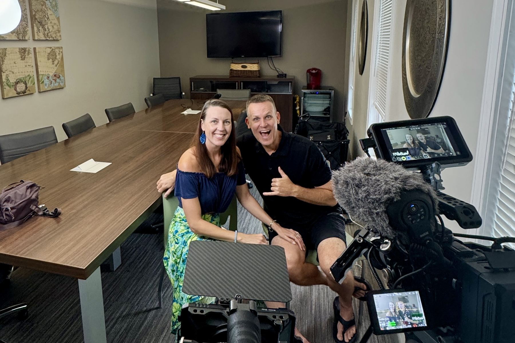 Two people smiling beside a camera rig in a conference room